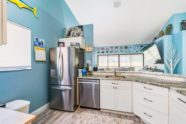 kitchen featuring light hardwood / wood-style floors, light stone countertops, white cabinetry, and stainless steel appliances