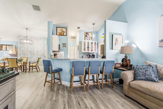 kitchen with decorative light fixtures, light hardwood / wood-style flooring, and a kitchen bar