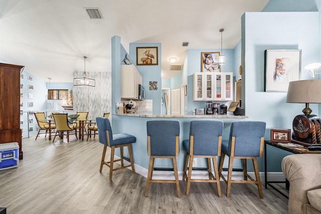 kitchen featuring hanging light fixtures, a kitchen breakfast bar, kitchen peninsula, and light wood-type flooring