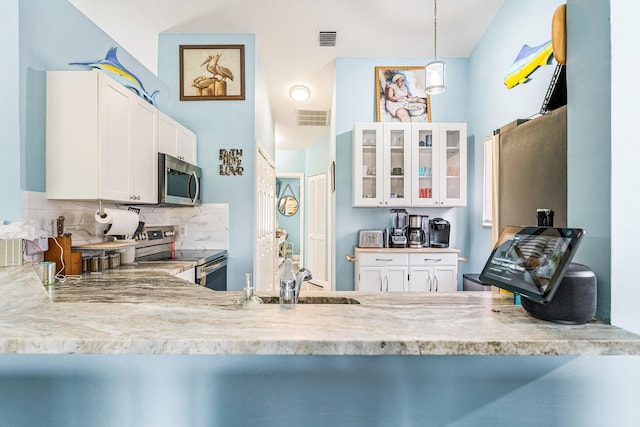 kitchen with stainless steel appliances, white cabinets, backsplash, and decorative light fixtures