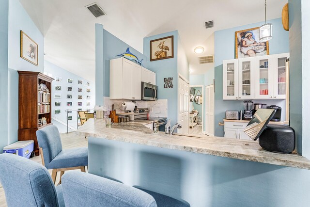 kitchen with decorative light fixtures, kitchen peninsula, white cabinets, and appliances with stainless steel finishes