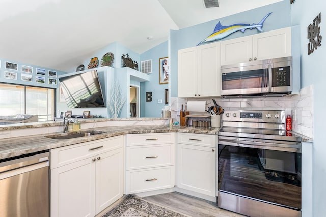 kitchen with white cabinetry, sink, light stone counters, and stainless steel appliances