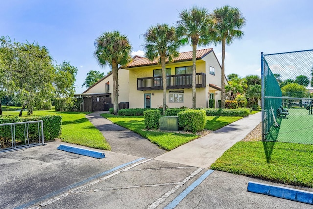 view of front of house with a balcony and a front lawn