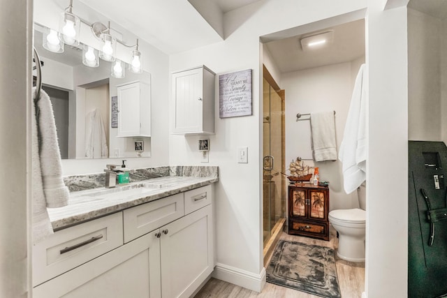 bathroom with a shower with door, vanity, hardwood / wood-style flooring, and toilet