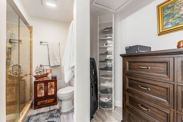 bathroom with walk in shower, toilet, and hardwood / wood-style floors