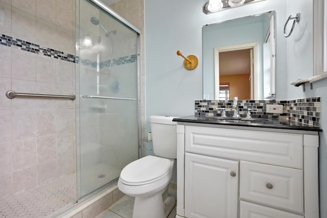 bathroom featuring tile patterned floors, decorative backsplash, a shower with door, and vanity