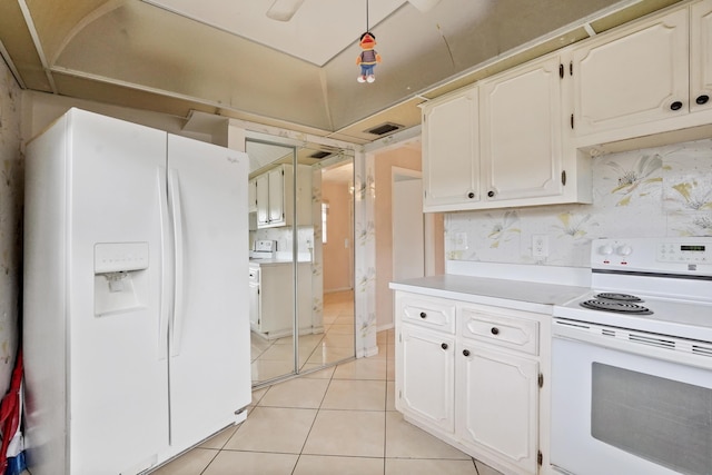 kitchen with white cabinets, light tile patterned floors, and white appliances