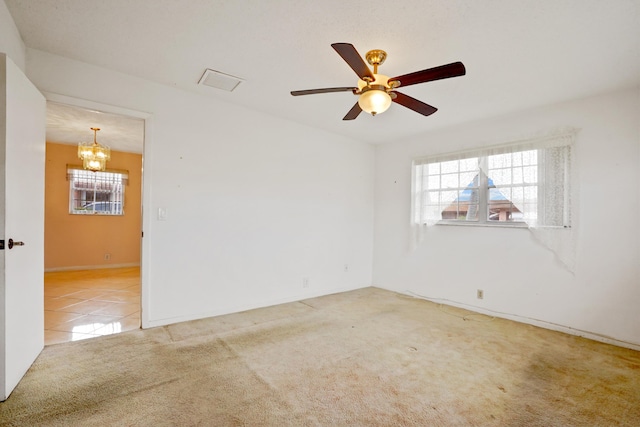 carpeted spare room featuring ceiling fan with notable chandelier