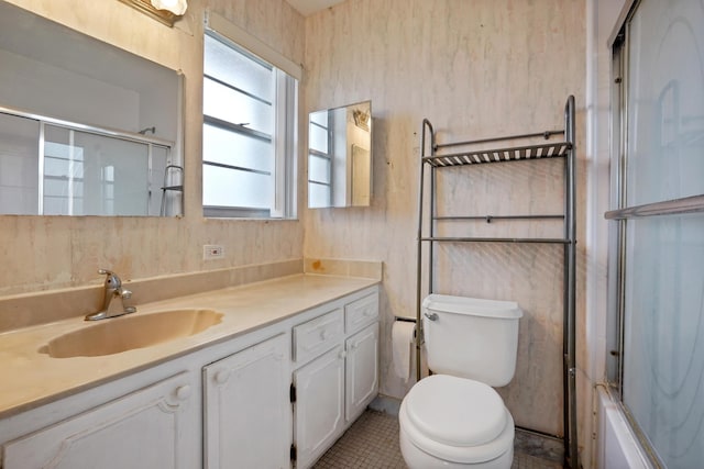 full bathroom with tile patterned floors, vanity, toilet, and bath / shower combo with glass door