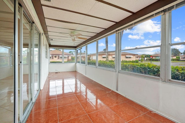 unfurnished sunroom featuring a paneled ceiling, ceiling fan, and a healthy amount of sunlight