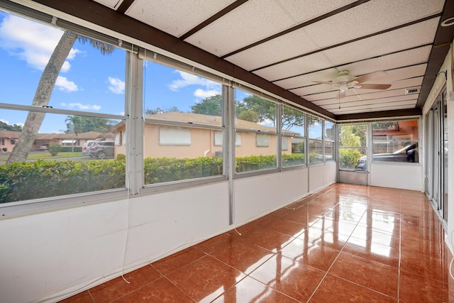 unfurnished sunroom featuring a drop ceiling and ceiling fan