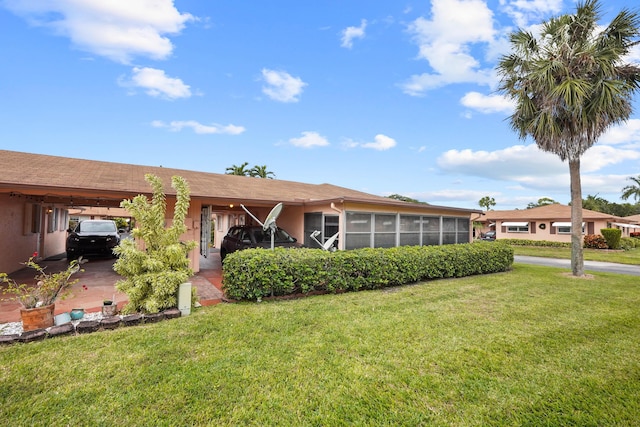 ranch-style house featuring a front yard, a carport, and a sunroom