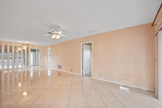 tiled empty room featuring ceiling fan with notable chandelier