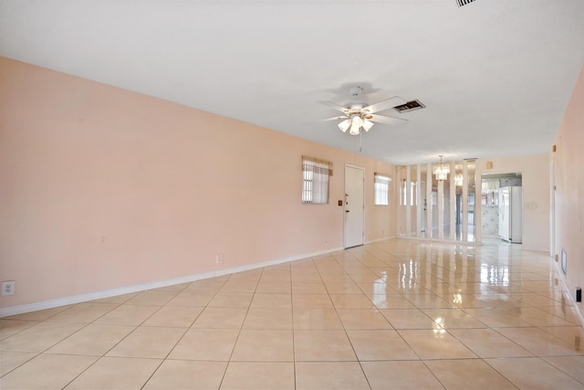 unfurnished room featuring light tile patterned floors and ceiling fan with notable chandelier