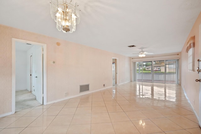 tiled spare room with ceiling fan with notable chandelier