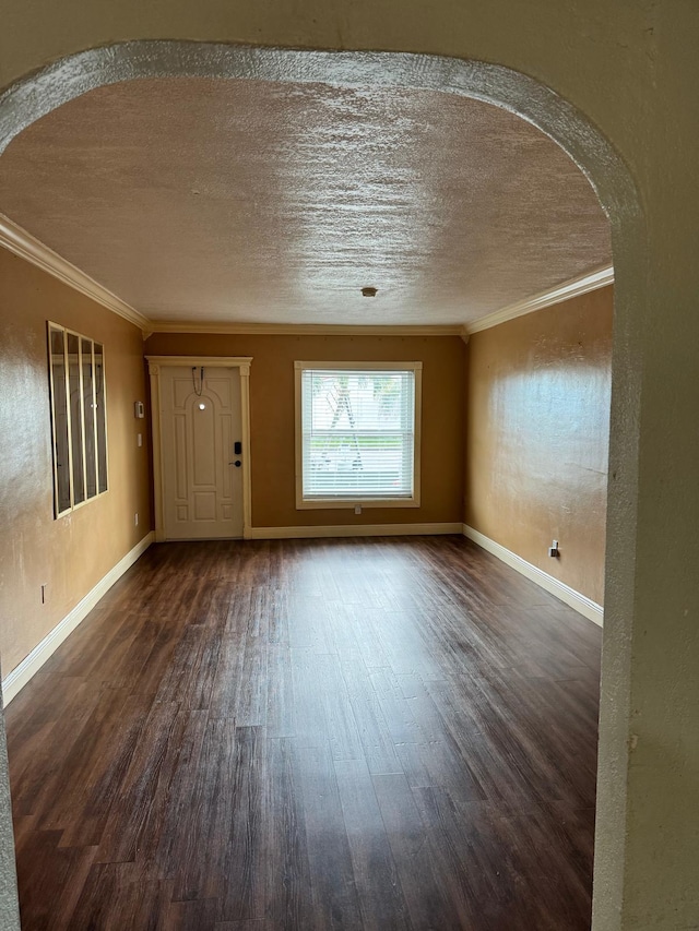 spare room with a textured ceiling, ornamental molding, and dark wood-type flooring