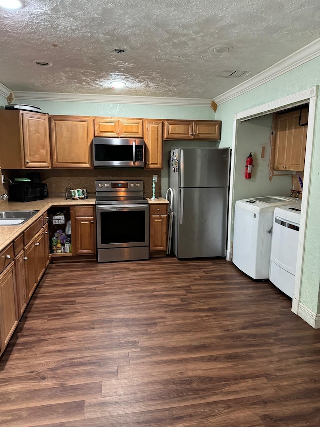 kitchen with appliances with stainless steel finishes, dark hardwood / wood-style flooring, ornamental molding, sink, and washer and dryer