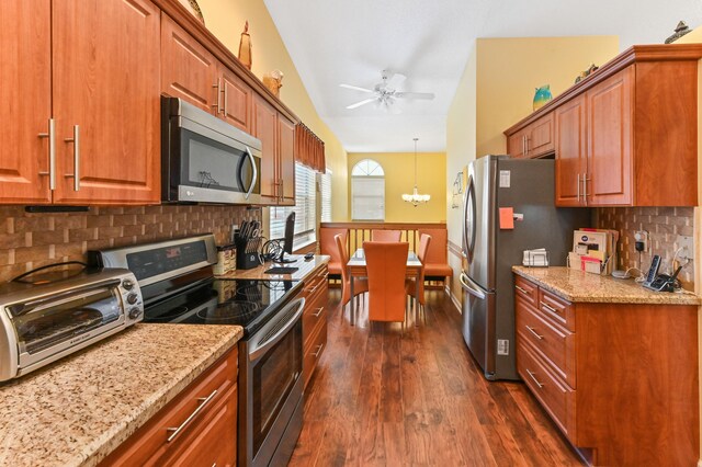 kitchen with backsplash, light stone counters, stainless steel appliances, dark hardwood / wood-style floors, and lofted ceiling