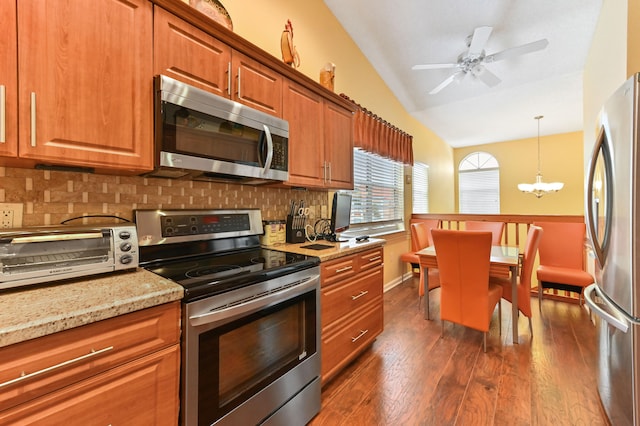 kitchen with backsplash, light stone counters, stainless steel appliances, vaulted ceiling, and dark wood-type flooring