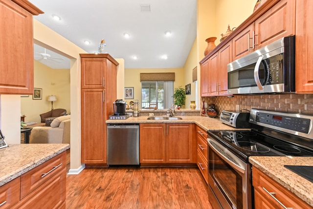 kitchen with backsplash, stainless steel appliances, hardwood / wood-style flooring, and ceiling fan