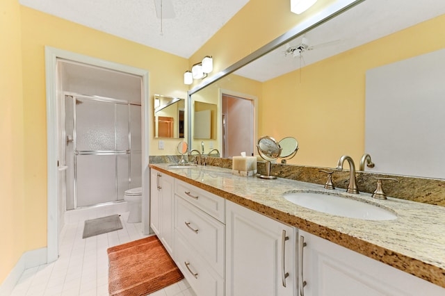 bathroom featuring tile patterned flooring, a textured ceiling, toilet, vanity, and a shower with shower door