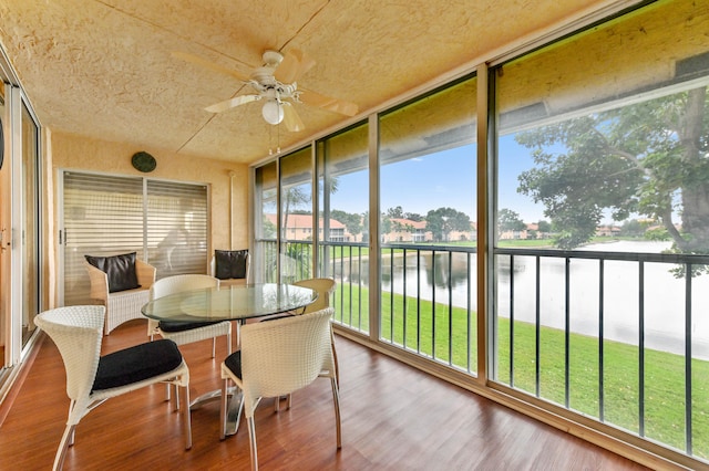 sunroom / solarium featuring ceiling fan and a water view