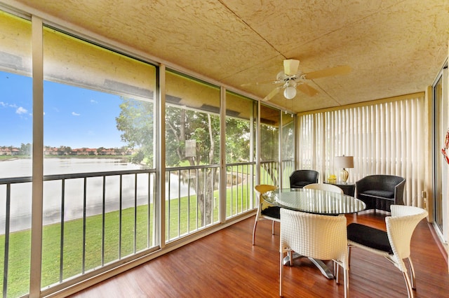 sunroom / solarium featuring a water view and ceiling fan