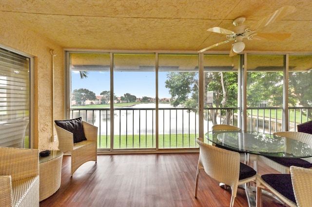 sunroom / solarium featuring ceiling fan and a water view