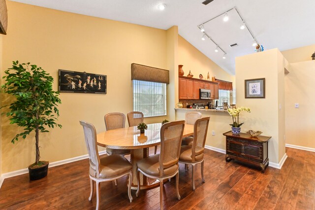 dining space with track lighting, dark hardwood / wood-style floors, and lofted ceiling