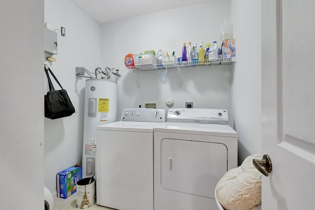 laundry area featuring a textured ceiling, water heater, and washing machine and clothes dryer