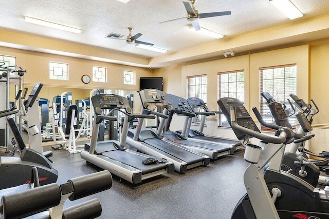 exercise room with ceiling fan and a textured ceiling