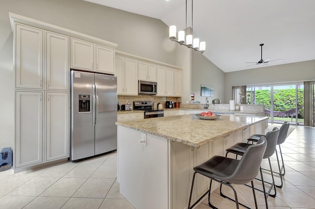 kitchen with ceiling fan, stainless steel appliances, high vaulted ceiling, kitchen peninsula, and a breakfast bar