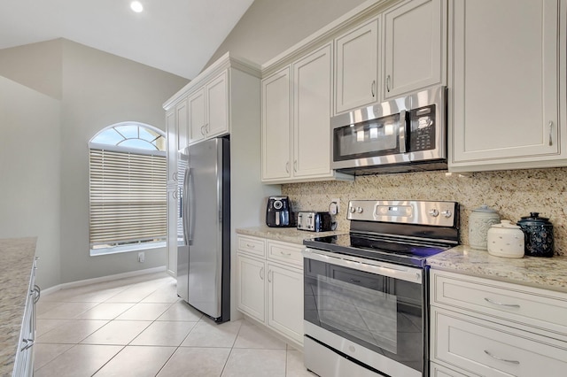 kitchen with backsplash, light tile patterned floors, stainless steel appliances, and vaulted ceiling