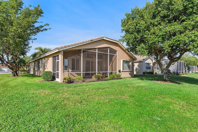 rear view of house with a sunroom and a lawn