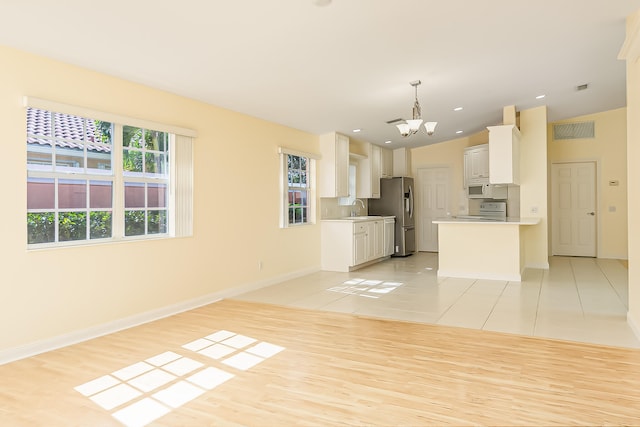 kitchen with white appliances, vaulted ceiling, sink, decorative light fixtures, and white cabinets