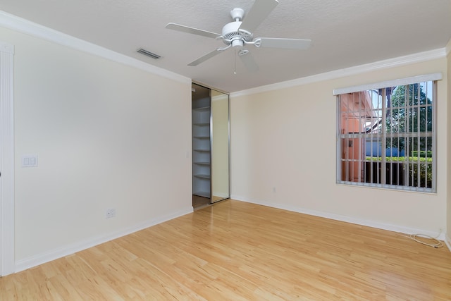 empty room with ceiling fan, ornamental molding, a textured ceiling, and hardwood / wood-style flooring