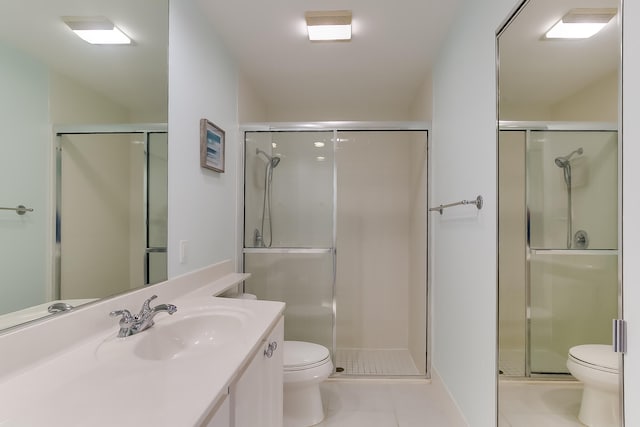 bathroom featuring tile patterned floors, vanity, toilet, and a shower with door