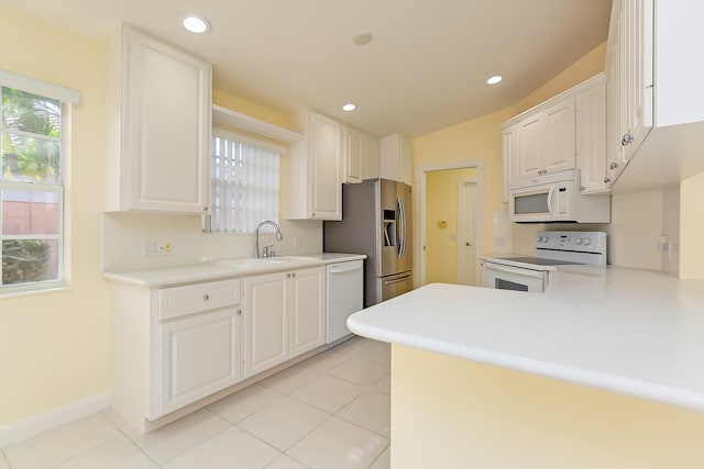 kitchen with white cabinets, sink, white appliances, and kitchen peninsula