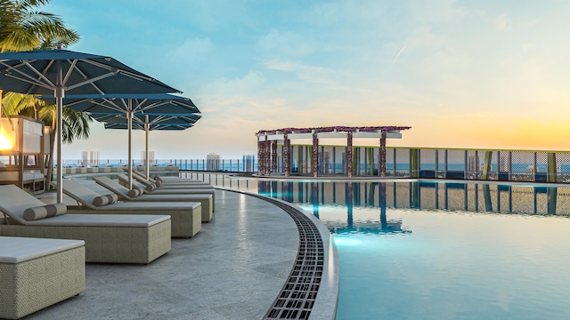 pool at dusk featuring a water view