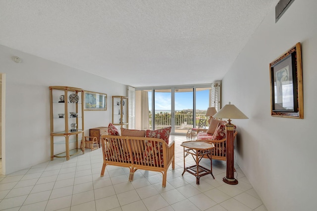 living room featuring a wall of windows, light tile patterned floors, and a textured ceiling