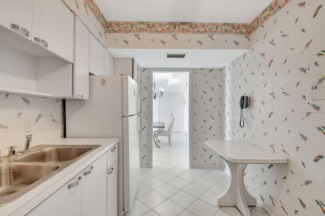 kitchen featuring sink, white cabinets, white fridge, and light tile patterned floors