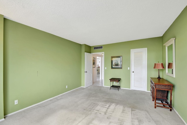 unfurnished room featuring a textured ceiling and light carpet