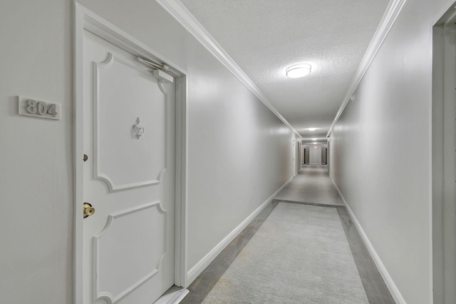 hall with a textured ceiling and ornamental molding