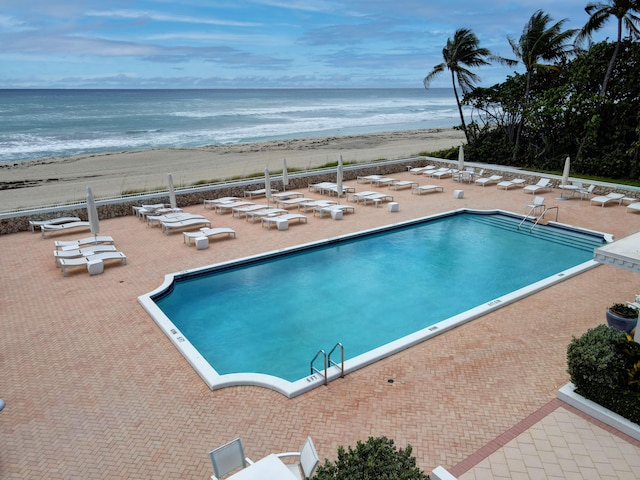 view of swimming pool with a view of the beach, a patio, and a water view