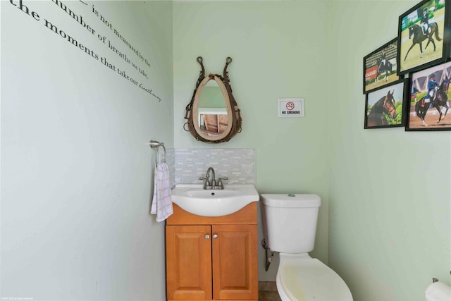 bathroom featuring vanity, toilet, and tasteful backsplash