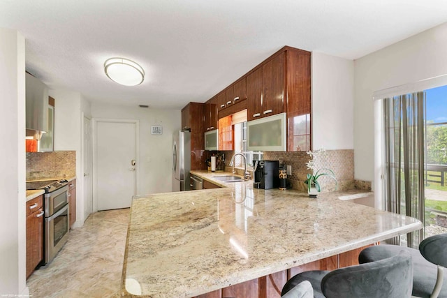 kitchen with kitchen peninsula, decorative backsplash, sink, and appliances with stainless steel finishes