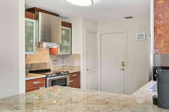 kitchen with a textured ceiling, tasteful backsplash, light stone counters, and stainless steel range with electric cooktop