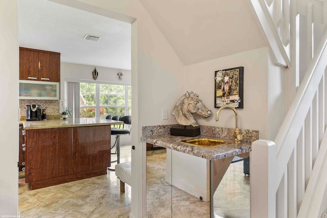 kitchen featuring lofted ceiling, sink, tasteful backsplash, kitchen peninsula, and a breakfast bar area