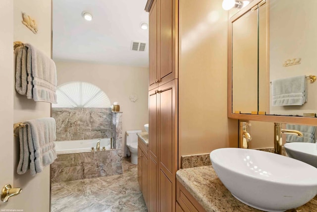 bathroom with vanity, toilet, and tiled tub