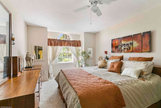 bedroom with ceiling fan, light carpet, and a textured ceiling